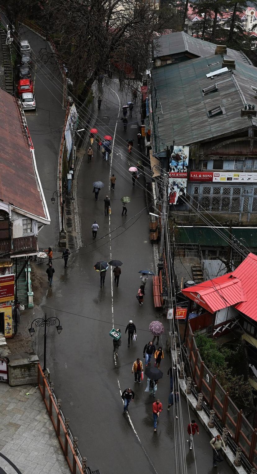 Bird-eye view of Mall Road Shimla in rain with colourful umbrellas walking between colonial-era buildings