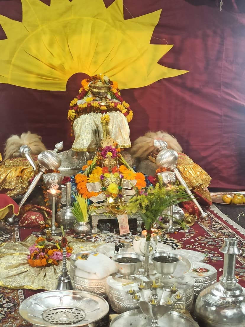 A deity's temporary camp altar during Kullu Dussehra with silver vessels, oil lamps and marigold