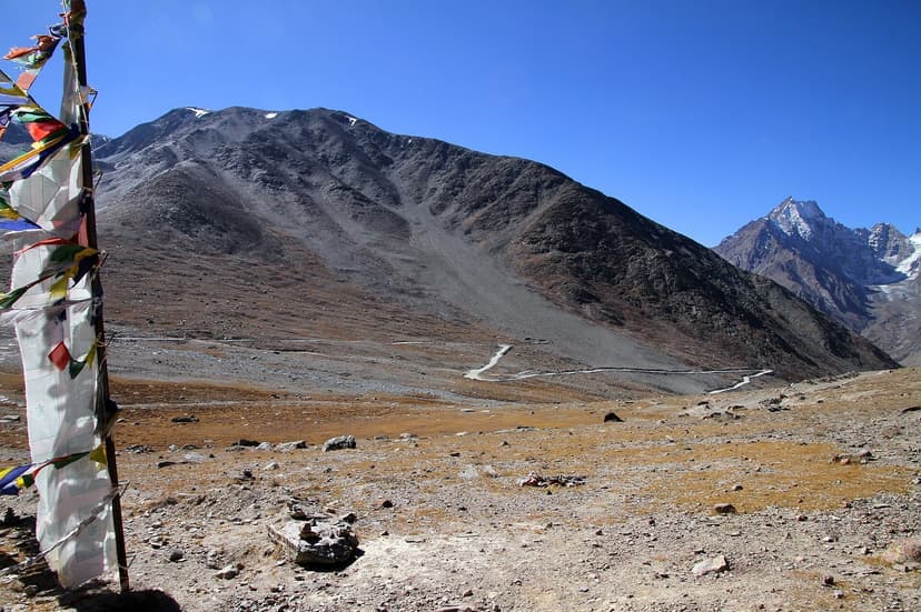 Kunzum Pass with prayer flags and a barren high-altitude landscape, the road snaking down to Spiti