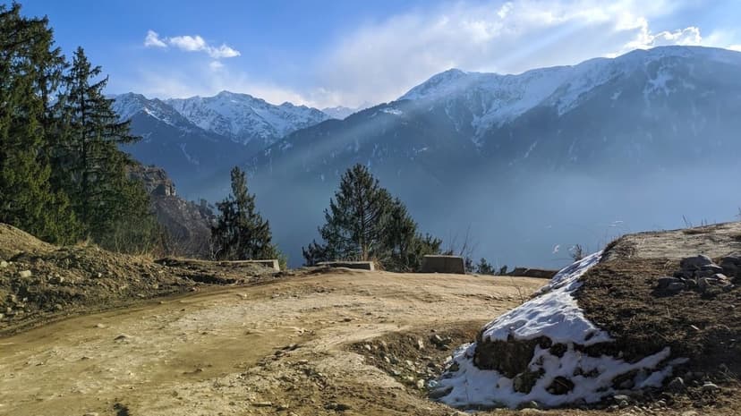 A forested ridge trail with snow peaks and morning mist above Sethan toward the Hampta Pass