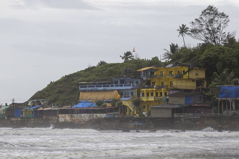 Colourful stacked guesthouses on the green Arambol headland above the surf in North Goa
