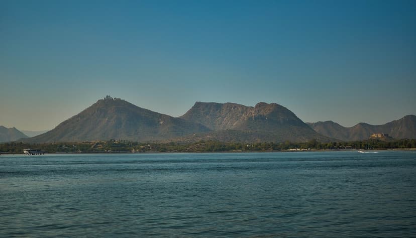 Fateh Sagar Lake, Udaipur, blue water with Aravalli hills behind and the white Monsoon Palace perched on a hilltop to the left.