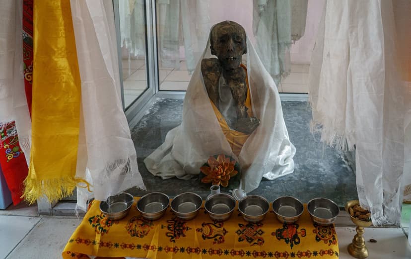 The naturally preserved 500-year-old Buddhist monk Sangha Tenzin in a glass case at Gue Monastery in Spiti, draped in white khata scarves with offerings in front