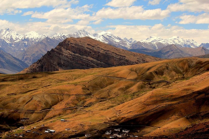 Komic village in Spiti sitting in a brown high-altitude bowl at 4,587 metres with snow-capped Himalayan peaks ringing the horizon