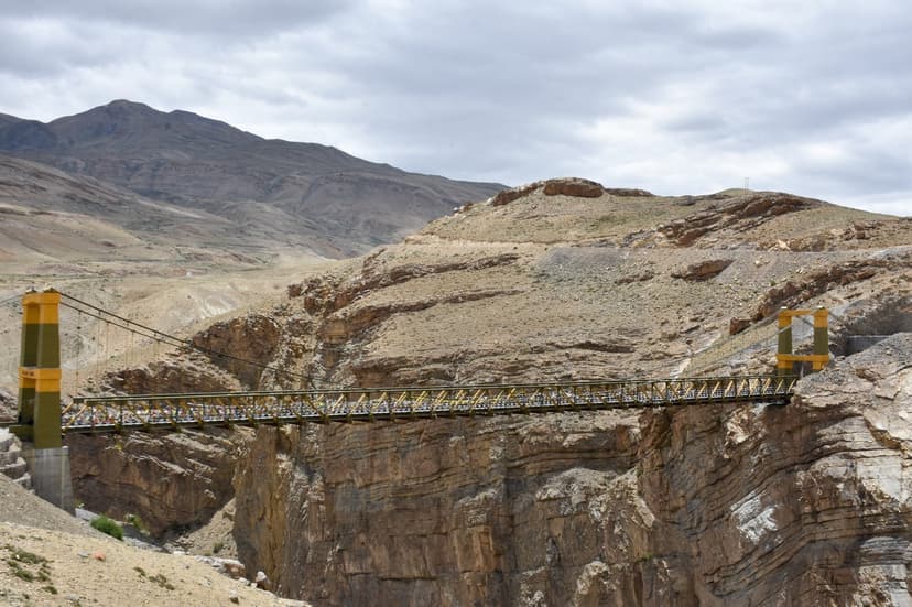 Yellow Chicham suspension bridge spanning a deep gorge in Spiti, with mountains in the background