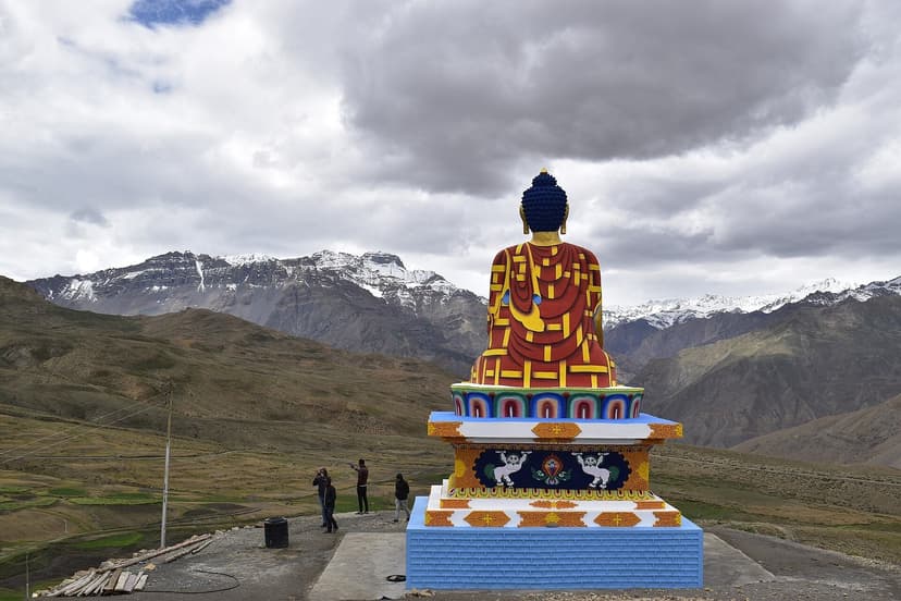 Red-and-gold seated Buddha statue at Langza village in Spiti Valley, facing snow-capped Himalayan ranges at 4,420 metres