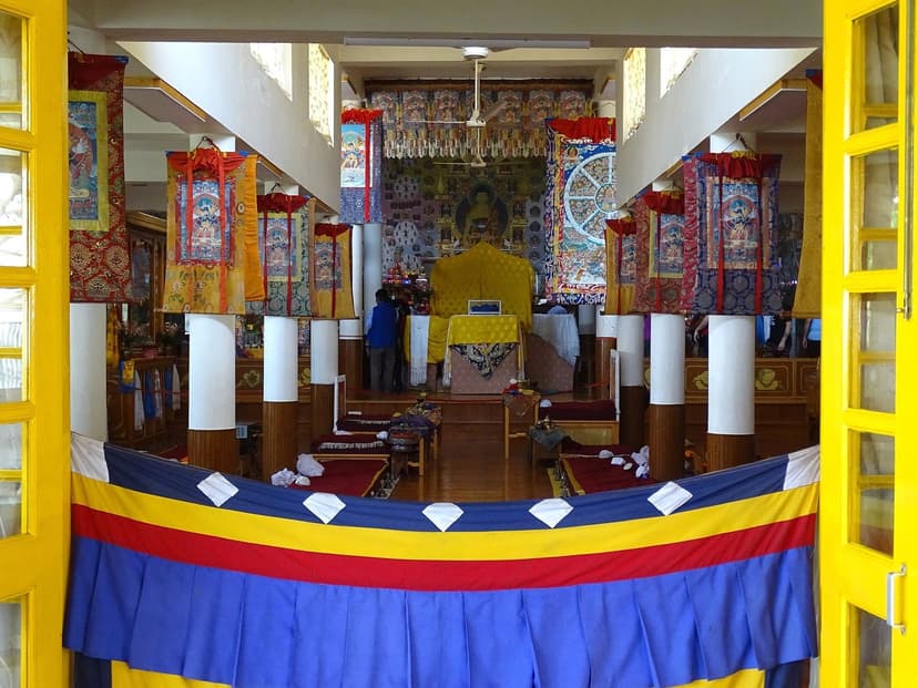 Interior of the Main Monks Hall at Tsuglagkhang Complex in McLeod Ganj, with Buddha statue, thangka paintings, and Tibetan flag