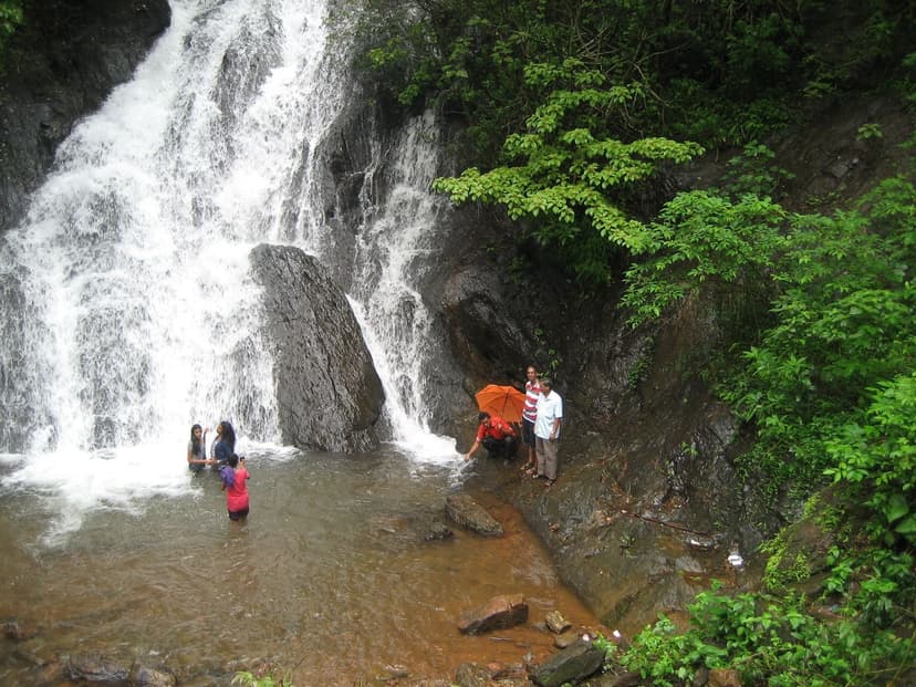 Seasonal Bamanbudo Waterfall in heavy flow with visitors standing beside and in the water
