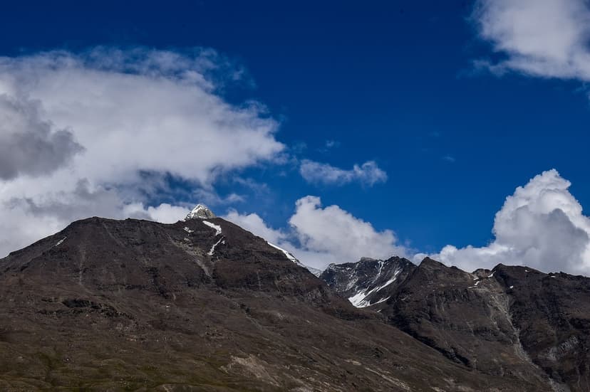 Ghepan Goh Peak at 5,870 metres seen from Sissu village on the north side of the Atal Tunnel, a rocky dark pyramid of a peak with clouds curling around the summit