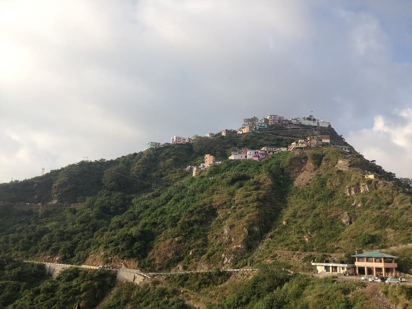 Naina Devi temple town crowning a steep green ridge in Bilaspur district, with the approach road switchbacking below