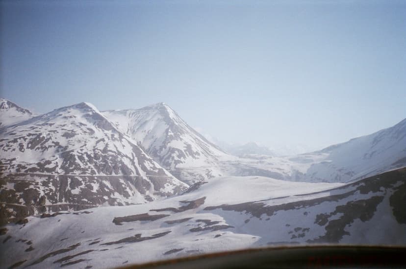 Aerial-style view of snow-covered Lahaul ridges in winter, blue-grey sky, ridgelines fading into haze, no settlement visible