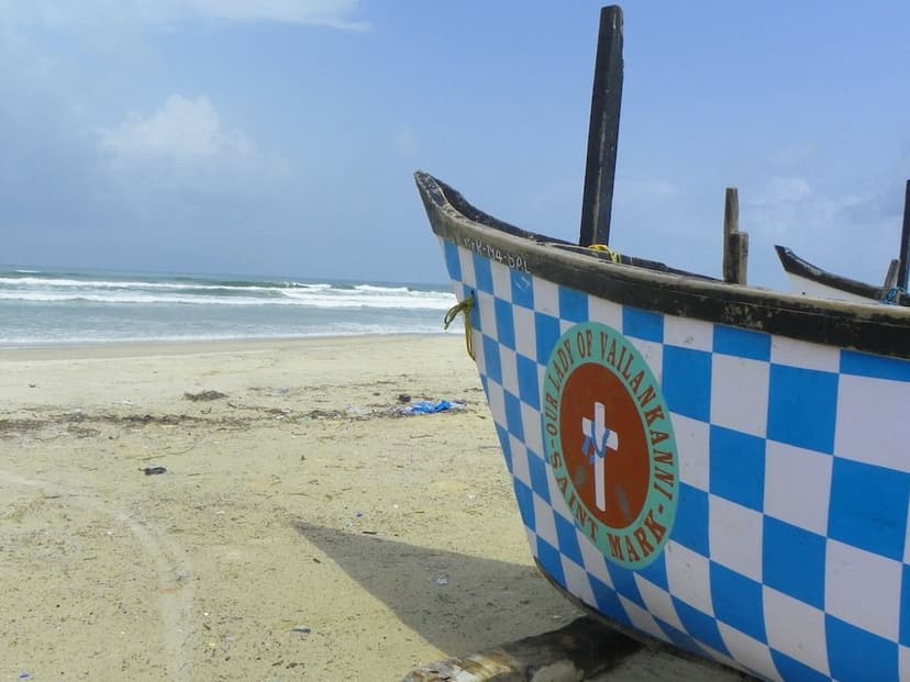 Blue and white wooden fishing boat pulled onto Benaulim beach with the sea beyond