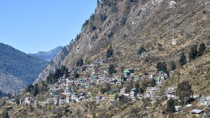 Mountain village clinging to a steep slope with colorful houses among trees, Parvati-Kullu area, Himachal Pradesh