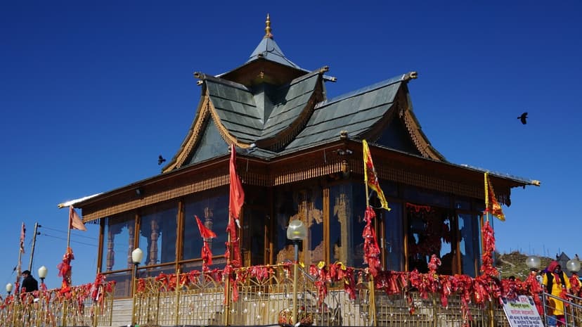 Hatu Mata Temple at 3,400m on Hatu Peak above Narkanda — a pagoda-style kath-kuni temple with dark wooden pillars and red prayer flags tied to its railings