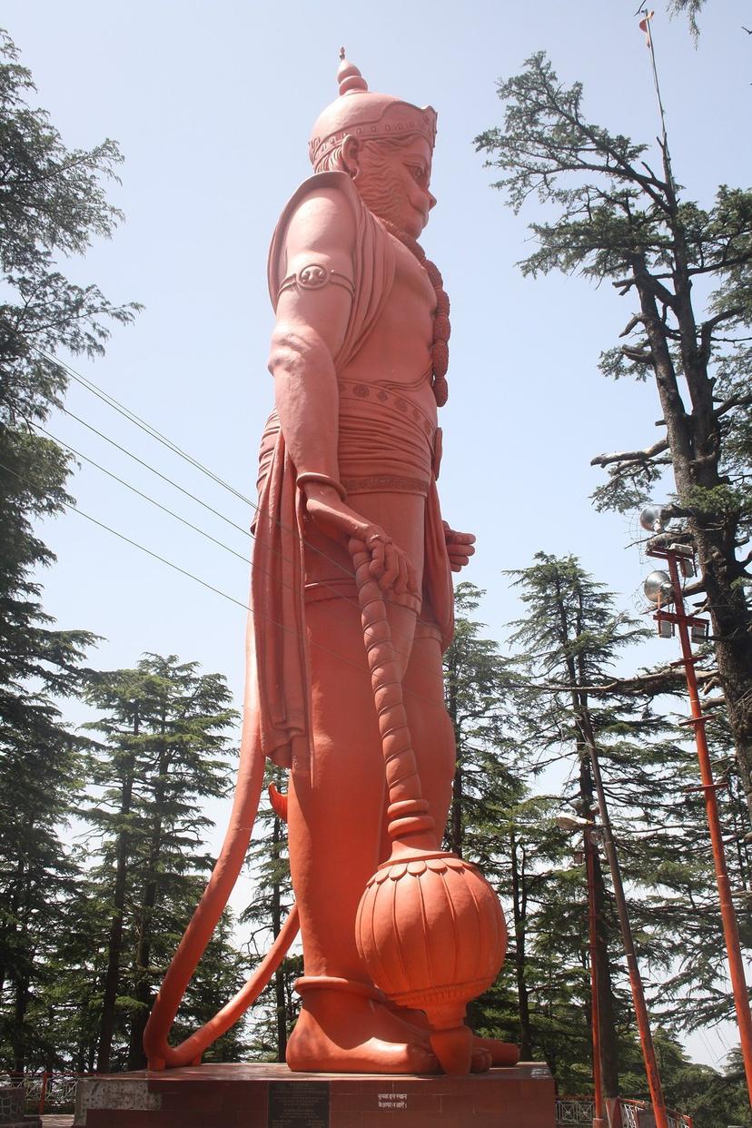 The giant orange Hanuman statue at Jakhu temple, Shimla, rising above deodar trees