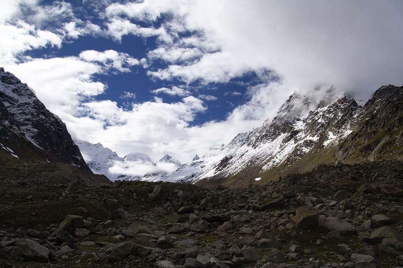 A rocky moraine valley below snow peaks high on the Hampta Pass route beyond Sethan