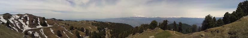 Panoramic view from Dainkund Peak at 2755 metres showing snow patches, deodar ridgelines and the snow-covered Pir Panjal on the horizon