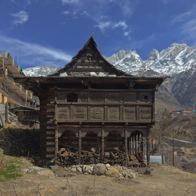 A traditional Kinnauri kath-kuni wooden house in Sangla with snow peaks behind