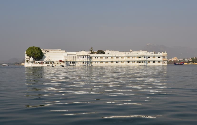 The white Taj Lake Palace hotel floating on Lake Pichola in Udaipur, a long low marble palace on a small island with hills faint behind.