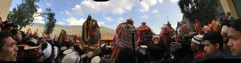 Panorama of dozens of deity palanquins with silver mohras and marigold, surrounded by crowds at Dhalpur, Kullu