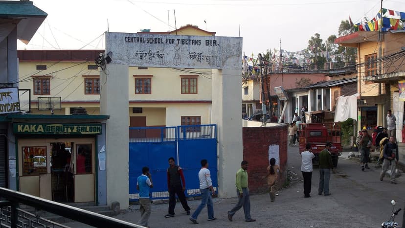 Central School for Tibetans entrance with shop fronts and pedestrians on the main street through the Bir Tibetan Colony at Chaugan
