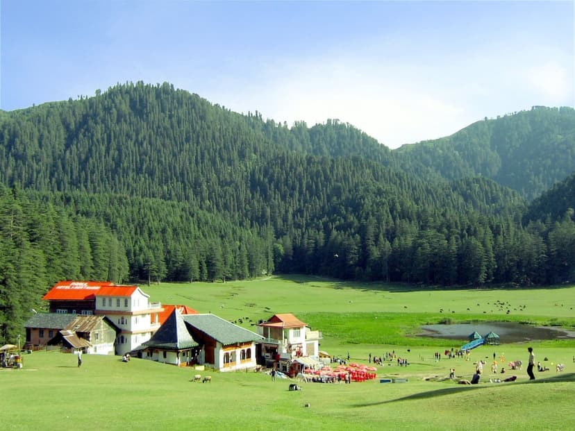 Khajjiar meadow with hotel buildings at the edge of the green saucer, deodar-covered hills rising behind
