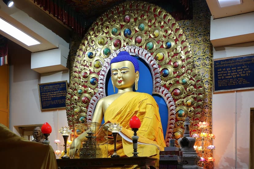 Golden Buddha statue inside Namgyal Monastery in McLeod Ganj, Dharamshala, the Dalai Lamas main temple, the figure seated on a lotus throne surrounded by colourful Tibetan iconography and offerings