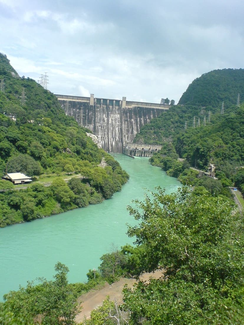 Bhakra Dam concrete gravity wall towering over the emerald Sutlej river gorge with forested Shivalik hills on both sides