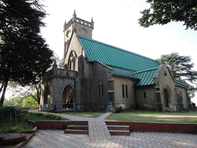 Christ Church at Kasauli with green sloping roof and Gothic arched doors over a paved approach
