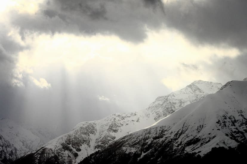 Snow-covered Himalayan peaks above the Great Himalayan National Park with sunbeams breaking through cloud