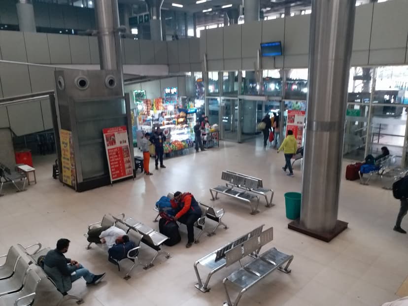 Interior of Kashmere Gate ISBT in Delhi with steel benches, snack stalls and a passenger information screen