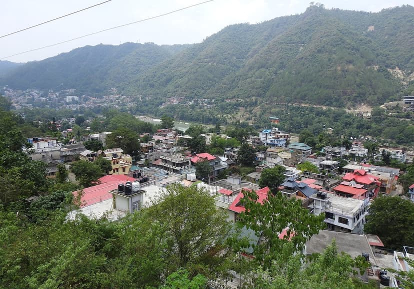 View across Mandi town in Himachal Pradesh, dense red and green roofs in a river valley ringed by forested hills