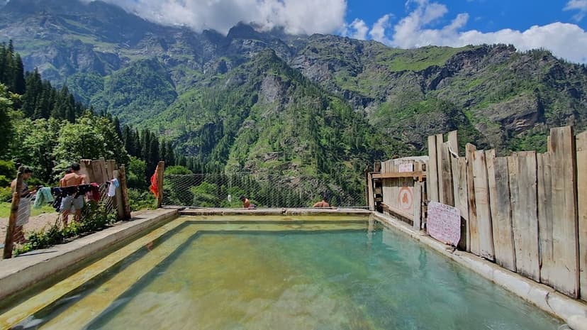 Stone hot-spring bathing pool at Kheerganga with mountains behind