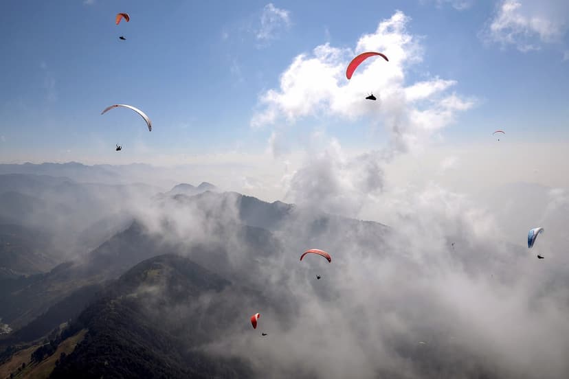 Several paragliders in the air over the Bir-Billing valley among cumulus clouds