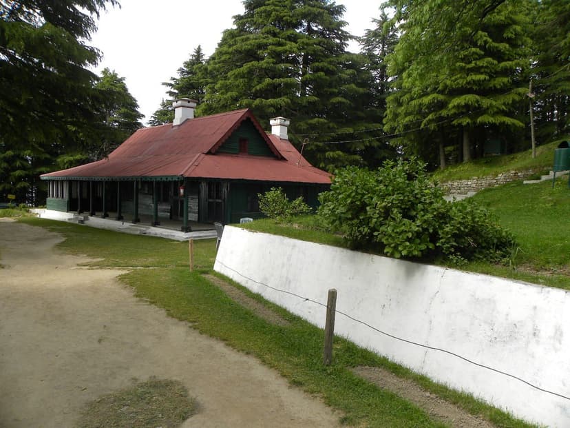Kalatop Forest Rest House, colonial-era green wooden bungalow with red tin roof among deodars