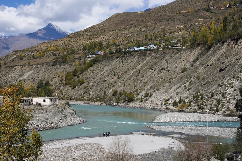 Chandra and Bhaga rivers meeting at Tandi in Lahaul, turquoise and grey-green water merging between stony banks under autumn hillsides