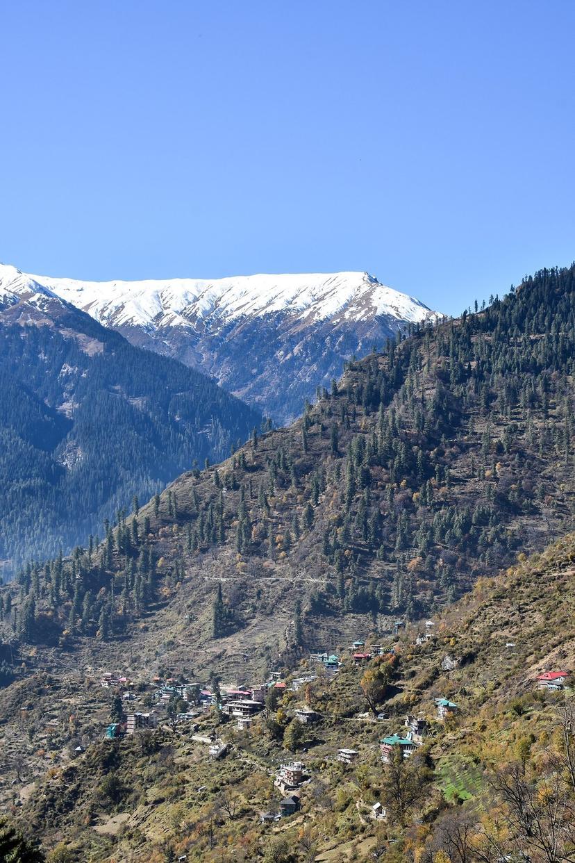 Tosh village Himachali houses on steep hillside with snow capped peaks above Parvati Valley