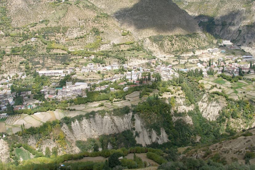 Keylong town in Lahaul built on a steep green hillside above the Bhaga river, with terraced fields and whitewashed buildings at about 3,080 metres