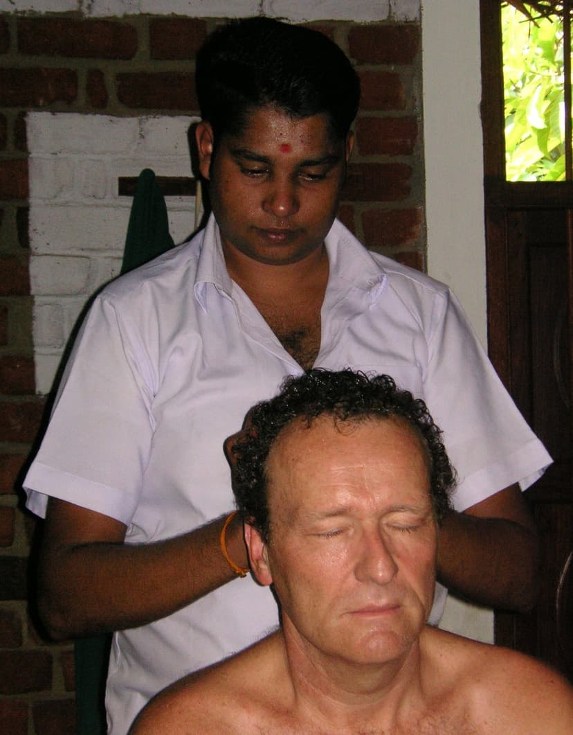 A therapist giving an oil head and neck massage to a seated person