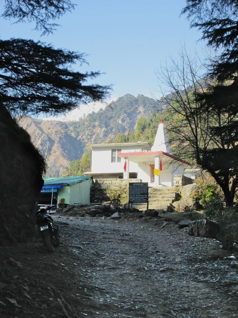 Small white Gallu Devi temple with red trim, at the start of the Triund forest check-post